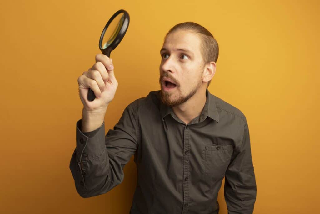 young-handsome-man-grey-shirt-holding-magnifying-glass-looking-it-intrigued 男性挑選商品